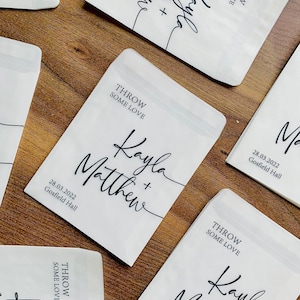 May include: White paper bags with black text that says "Throw some love" and "Kayla + Matthew" with the date "28.03.2022" and "Gosfield Hall".