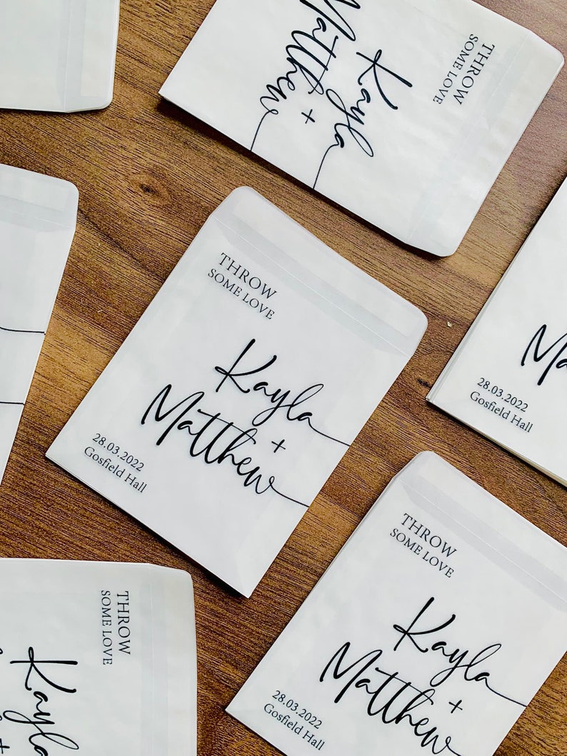 May include: White paper bags with black text that says "Throw some love" and "Kayla + Matthew" with the date "28.03.2022" and "Gosfield Hall".