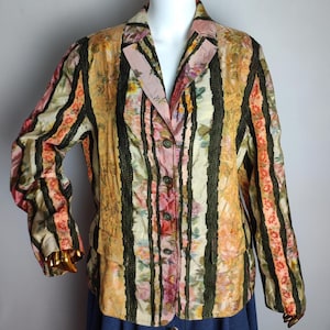 May include: A long-sleeved, button-up jacket with a floral and striped pattern in shades of pink, green, yellow, and orange. The jacket has a collar and a single button closure.