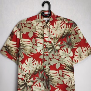 May include: A red short-sleeved button-down shirt with a tropical leaf print in shades of green and white.