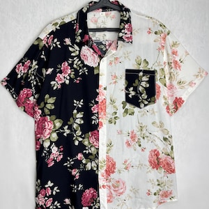May include: Short-sleeved shirt with a split design. One side is black with pink floral print, the other is white with pink floral print. Features a black pocket on the white side. The shirt is hanging on a black hanger.