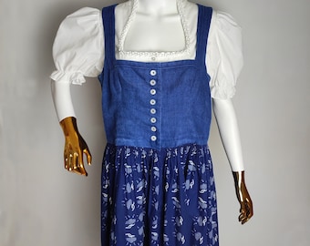Puede incluir: Un vestido de dirndl de mezclilla azul con una blusa blanca y un collar de perlas blancas. La falda tiene un estampado floral azul y blanco.