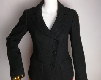 Puede incluir: Una chaqueta negra con cierre de un solo botón y dos bolsillos de solapa. La chaqueta tiene una silueta ligeramente ajustada y está hecha de una tela texturizada.