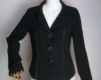 May include: A black blazer with a fitted silhouette and a single-breasted button closure. The blazer has a collar and long sleeves with a contrasting black trim.