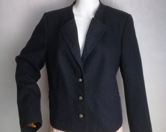 Puede incluir: Una chaqueta azul oscuro con cierre de un solo botón y cuatro botones plateados. La chaqueta tiene un cuello de muesca y un bolsillo en el lado izquierdo.