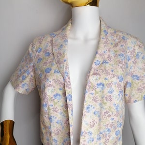 May include: A short-sleeved, light pink floral print jacket with a pointed collar and a V-neckline.