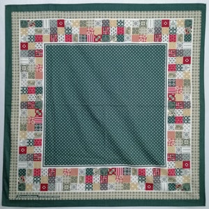 Könnte beinhalten: Ein grünes Stoffquadrat mit einem weißen Punktmuster in der Mitte. Der Rand ist ein Patchwork-Design mit roten, weißen und beigefarbenen Quadraten. Der Text "Donaldson The West Point Company" ist unten in Rot gedruckt.