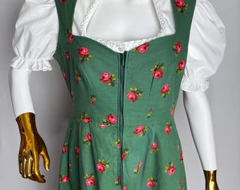 May include: A green dress with a floral pattern of red roses. The dress has a square neckline, a white ruffled collar, and white puff sleeves. A zipper runs down the front of the dress.