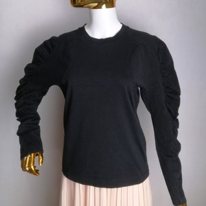 May include: Black long-sleeve shirt with gathered sleeves and a round neckline.