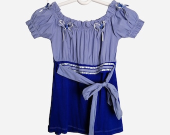 Puede incluir: Un vestido de cuadros azules y blancos con una falda azul y una cinta blanca atada a la cintura.