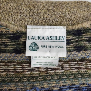 May include: Close-up of a textured wool garment with a patterned design in shades of brown, green, and blue. A white label reads "LAURA ASHLEY PURE NEW WOOL" with size information. Made in Great Britain.