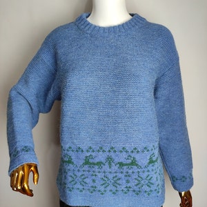 May include: A blue knitted jumper with a green and blue patterned design around the bottom hem.