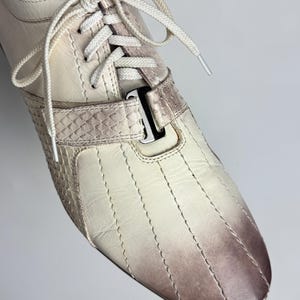 K&ouml;nnte beinhalten: Cremefarbener Ledersneaker mit Farbverlauf von Creme zu Braun an der Spitze. Mit wei&szlig;en Schn&uuml;rsenkeln, einem strukturierten Riemen und vertikalen N&auml;hten. Klassisches, sportliches Design f&uuml;r den Alltag.