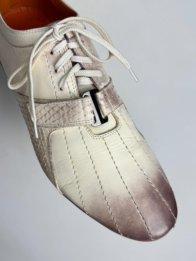 K&ouml;nnte beinhalten: Cremefarbener Ledersneaker mit Farbverlauf von Creme zu Braun an der Spitze. Mit wei&szlig;en Schn&uuml;rsenkeln, einem strukturierten Riemen und vertikalen N&auml;hten. Klassisches, sportliches Design f&uuml;r den Alltag.