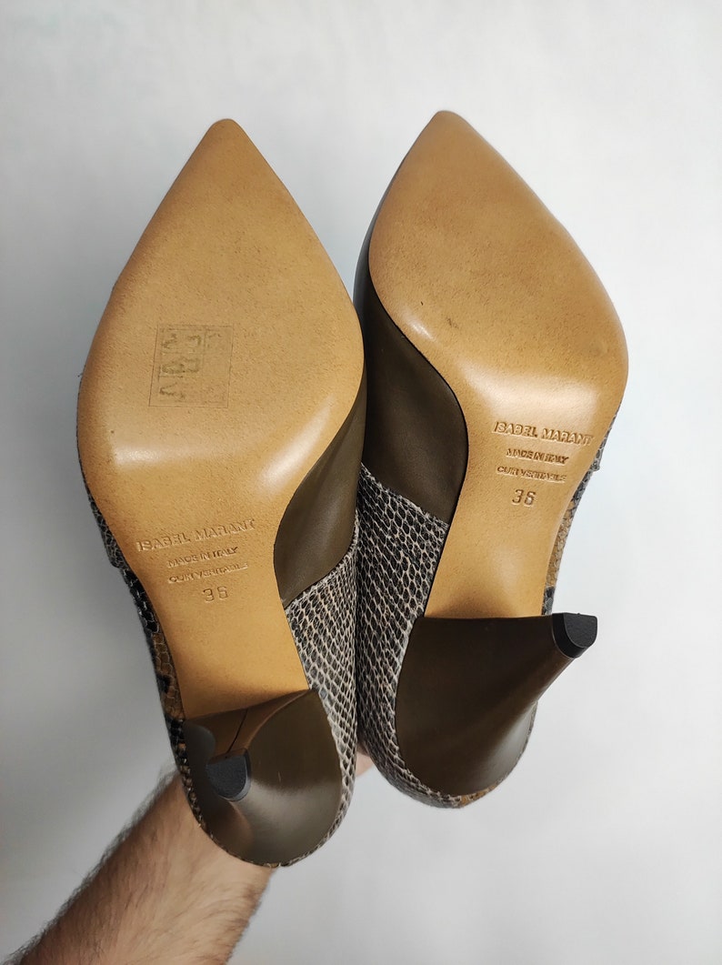 May include: A pair of brown and black snakeskin heeled boots with a pointed toe. The boots are made by Isabel Marant and are size 36.