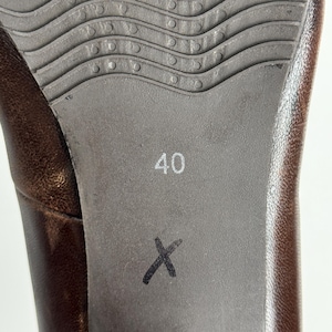 Puede incluir: Primer plano de la suela de un zapato de cuero marr&oacute;n. La suela es de color gris oscuro con un patr&oacute;n ondulado y texturizado y el n&uacute;mero "40" impreso en blanco. Una "X" negra est&aacute; marcada en la suela.