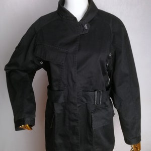 May include: A black utility jacket with a stand-up collar, a belt, and multiple pockets.