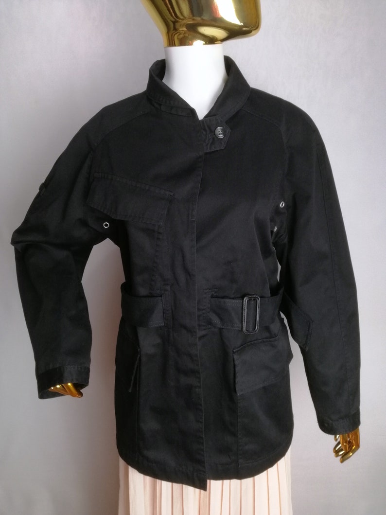 May include: A black utility jacket with a stand-up collar, a belt, and multiple pockets.