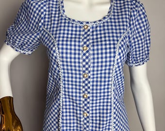 Puede incluir: Una blusa de botones de cuadros azules y blancos con ribete de crochet blanco y botones dorados.