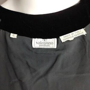 K&ouml;nnte beinhalten: Schwarzes Samt- und Seidenkleid mit einem wei&szlig;en Etikett mit der Aufschrift "valentino boutique" und "made in italy, fabrique en italie".