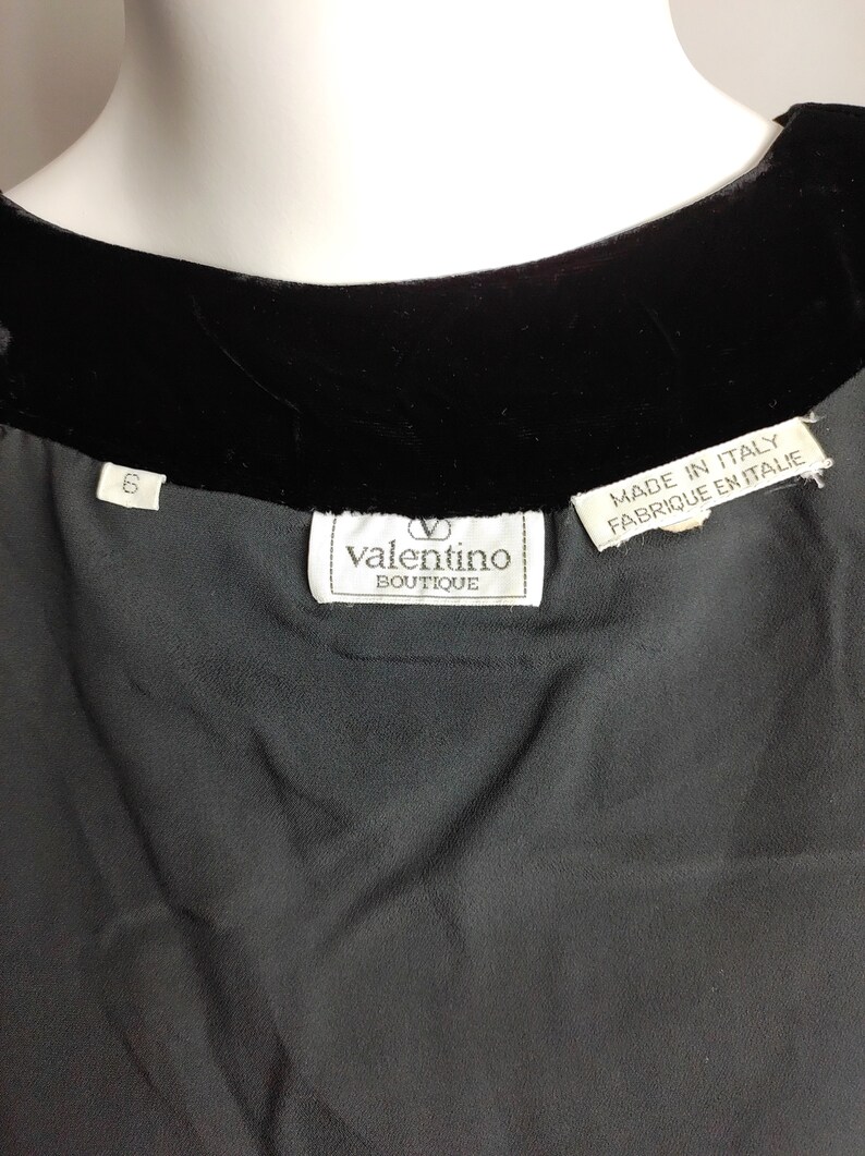 K&ouml;nnte beinhalten: Schwarzes Samt- und Seidenkleid mit einem wei&szlig;en Etikett mit der Aufschrift "valentino boutique" und "made in italy, fabrique en italie".