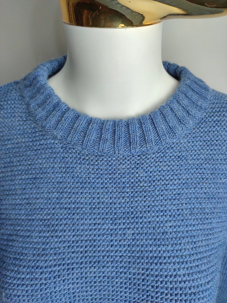 May include: A light blue knitted jumper with a round neckline.