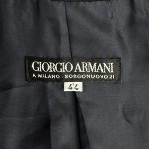 Pode incluir: Uma etiqueta preta Giorgio Armani com texto branco que diz "Giorgio Armani, A Milano, Borgonuvo 21" e uma etiqueta branca com o n&uacute;mero "44" nela.