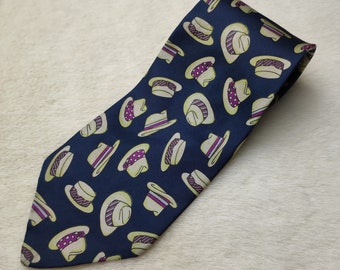 May include: A navy blue silk tie with a repeating pattern of white and purple hats. The hats have a variety of designs, including stripes, polka dots, and solid colors.