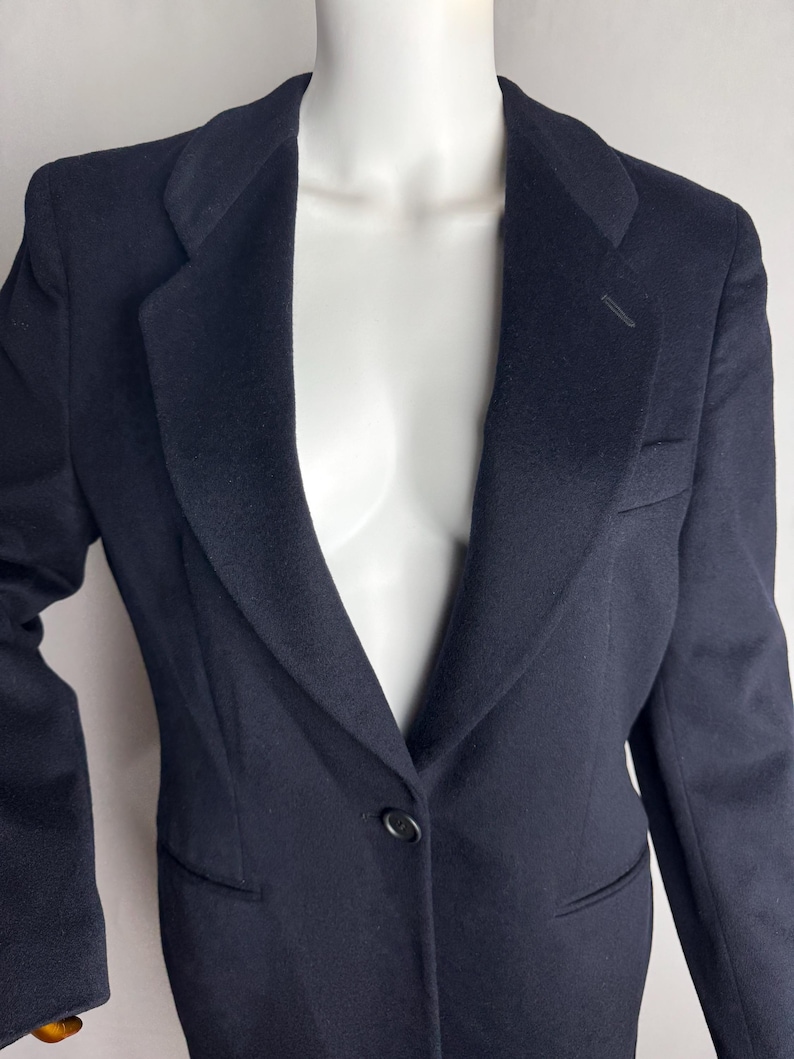 Pode incluir: Um blazer azul escuro com um fecho de bot&atilde;o &uacute;nico e lapela de entalhe.