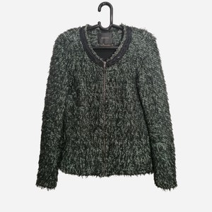 May include: A green and black tweed jacket with a zipper closure and a beaded trim around the neckline.