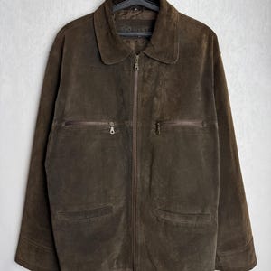 May include: A brown suede jacket with a zipper closure and two pockets on each side. The jacket has the word "GO WEST" printed on the front.