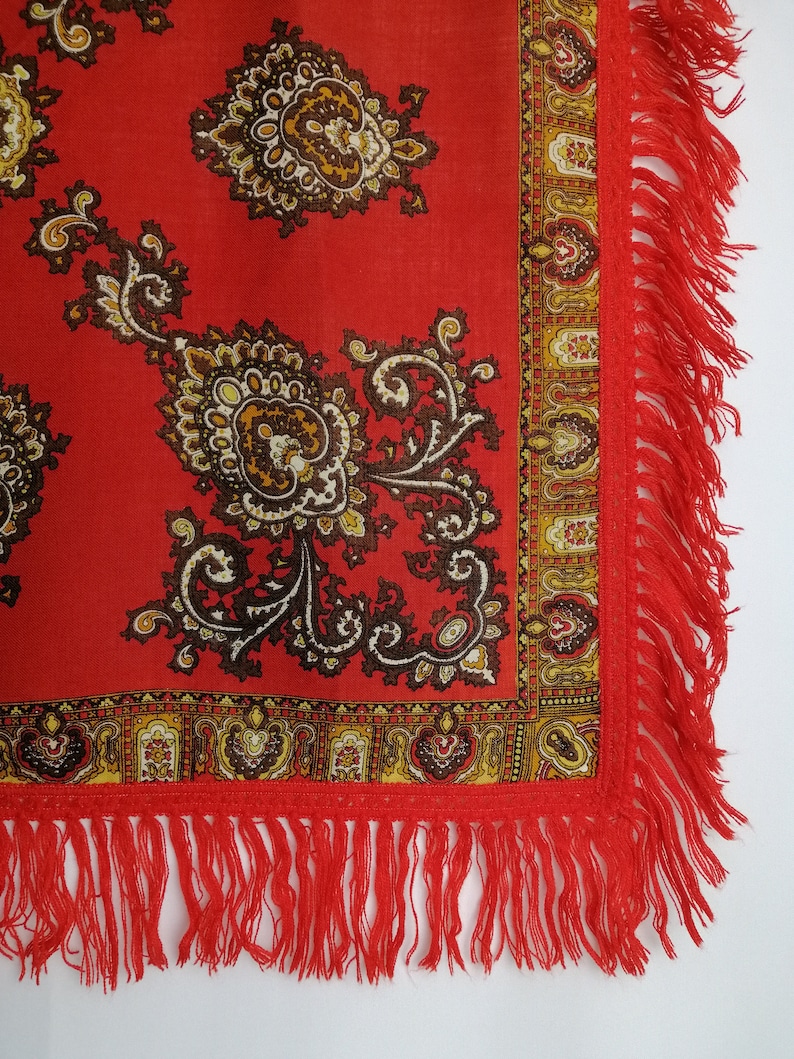 K&ouml;nnte beinhalten: Roter Schal mit Paisley-Muster und Fransenrand. Der Schal hat ein traditionelles Design mit braunen und goldenen Akzenten.