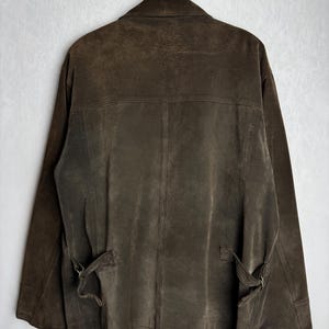 May include: A brown suede jacket with a zipper closure and a belt at the waist.