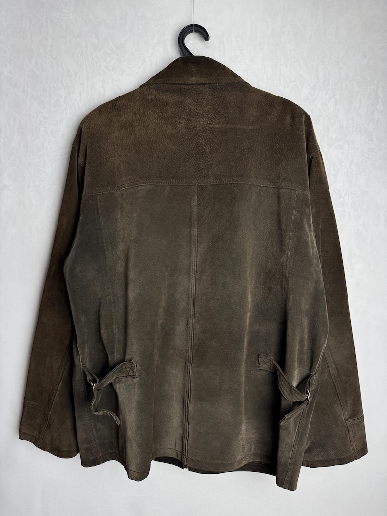 May include: A brown suede jacket with a zipper closure and a belt at the waist.