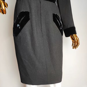 K&ouml;nnte beinhalten: Ein schwarzes Kleid mit Samtbesatz und Taschen. Das Kleid hat eine figurbetonte Silhouette und eine knielange L&auml;nge.