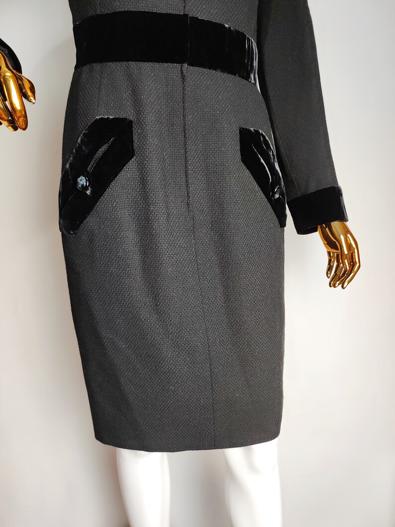 K&ouml;nnte beinhalten: Ein schwarzes Kleid mit Samtbesatz und Taschen. Das Kleid hat eine figurbetonte Silhouette und eine knielange L&auml;nge.