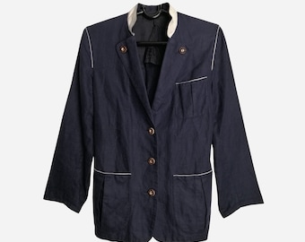 Puede incluir: Blazer azul marino con cuello y ribetes blancos. El blazer tiene tres botones, dos bolsillos delanteros y un pequeño bolsillo en el pecho. Las mangas son de tres cuartos.