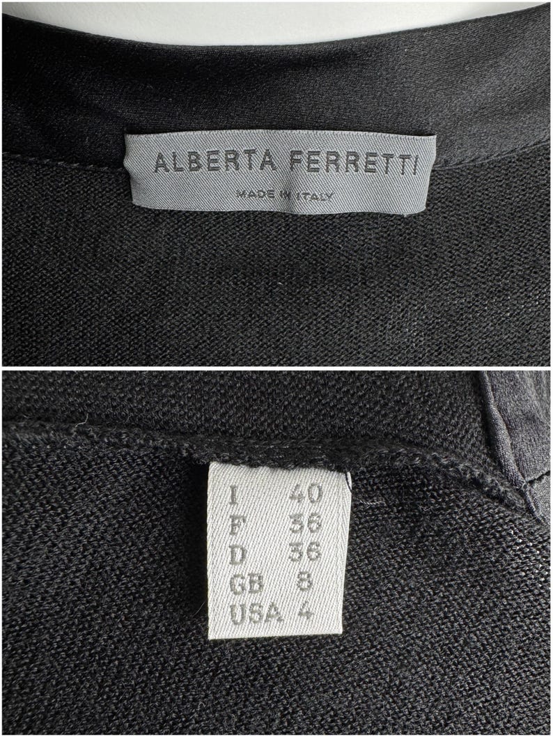 K&ouml;nnte beinhalten: Ein schwarzer Strickcardigan mit einem wei&szlig;en Etikett, auf dem "Alberta Ferretti" und "Made in Italy" steht. Das Etikett zeigt auch die Gr&ouml;&szlig;e in verschiedenen Gr&ouml;&szlig;ensystemen: I 40, F 36, D 36, GB 8, USA 4.