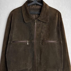 May include: A brown suede jacket with a zipper closure and multiple pockets. The jacket has a label that reads "GO WEST".