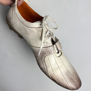 K&ouml;nnte beinhalten: Cremefarbener Ledersneaker mit strukturierter Spitze und Farbverlauf von Wei&szlig; nach Braun. Der Schuh hat wei&szlig;e Schn&uuml;rsenkel und eine braune Sohle. Der Innenraum ist orange.