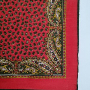 Puede incluir: Pa&ntilde;uelo rojo con estampado de cachemira y borde detallado. El pa&ntilde;uelo presenta un patr&oacute;n repetido de peque&ntilde;as formas de cachemira negras sobre un fondo rojo. El borde tiene un dise&ntilde;o de cachemira verde, amarillo y rosa.