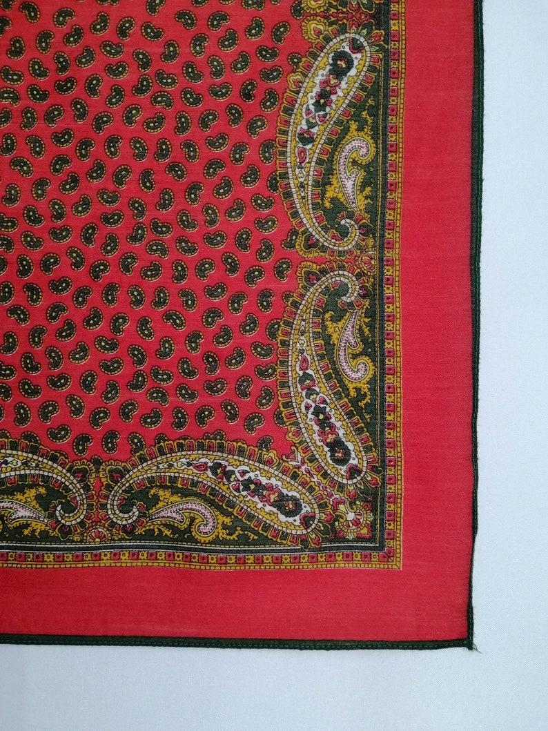Puede incluir: Pa&ntilde;uelo rojo con estampado de cachemira y borde detallado. El pa&ntilde;uelo presenta un patr&oacute;n repetido de peque&ntilde;as formas de cachemira negras sobre un fondo rojo. El borde tiene un dise&ntilde;o de cachemira verde, amarillo y rosa.