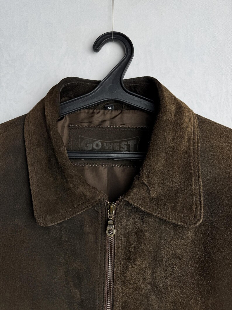 May include: A brown suede jacket with a zipper closure and a label that reads "GO WEST".