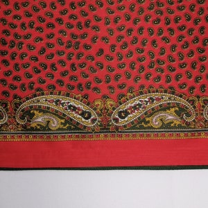 Puede incluir: Textil rojo con un estampado de cachemir de gotas negras y amarillas. El borde inferior presenta un dise&ntilde;o de cachemir m&aacute;s grande en rojo, amarillo, negro y blanco. Probablemente una bufanda o tela.