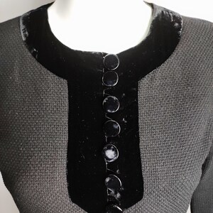 K&ouml;nnte beinhalten: Ein schwarzes Kleid mit einem Samtkragen und einer Reihe schwarzer Kn&ouml;pfe vorne.