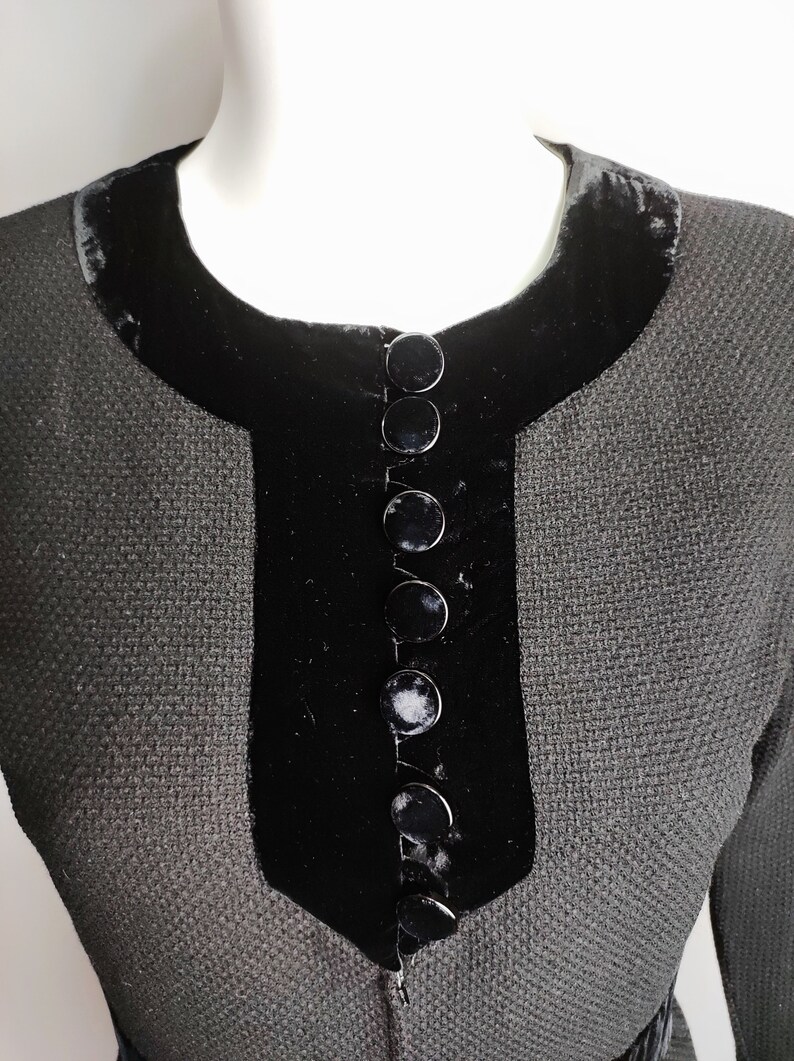 K&ouml;nnte beinhalten: Ein schwarzes Kleid mit einem Samtkragen und einer Reihe schwarzer Kn&ouml;pfe vorne.