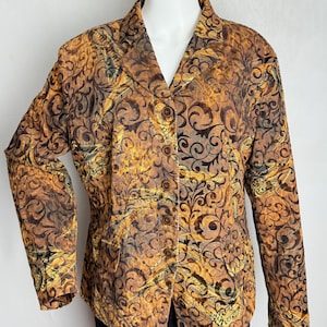 May include: A patterned blazer in shades of brown, gold, and black, with a swirling, ornate design. The jacket has a notched collar, long sleeves, and three brown buttons down the front. The blazer is displayed on a mannequin.