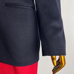 Pode incluir: Um blazer azul marinho com fecho de um &uacute;nico bot&atilde;o e um bolso no lado esquerdo. O blazer &eacute; feito de um tecido macio e texturizado.