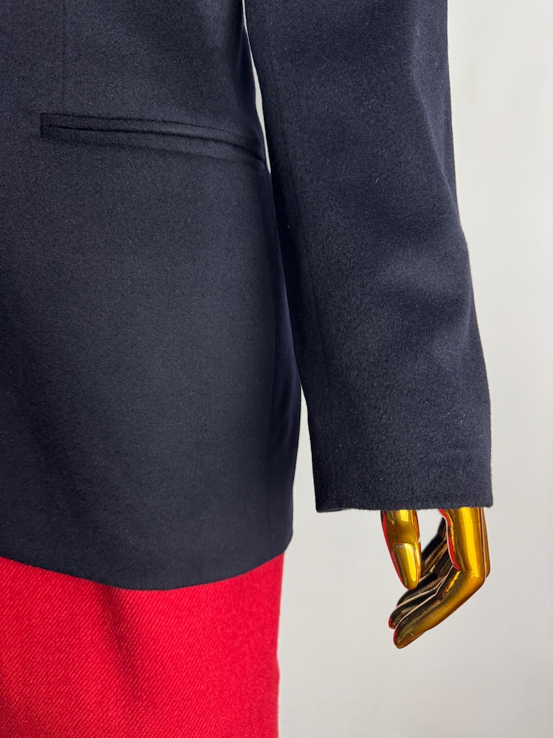 Pode incluir: Um blazer azul marinho com fecho de um &uacute;nico bot&atilde;o e um bolso no lado esquerdo. O blazer &eacute; feito de um tecido macio e texturizado.