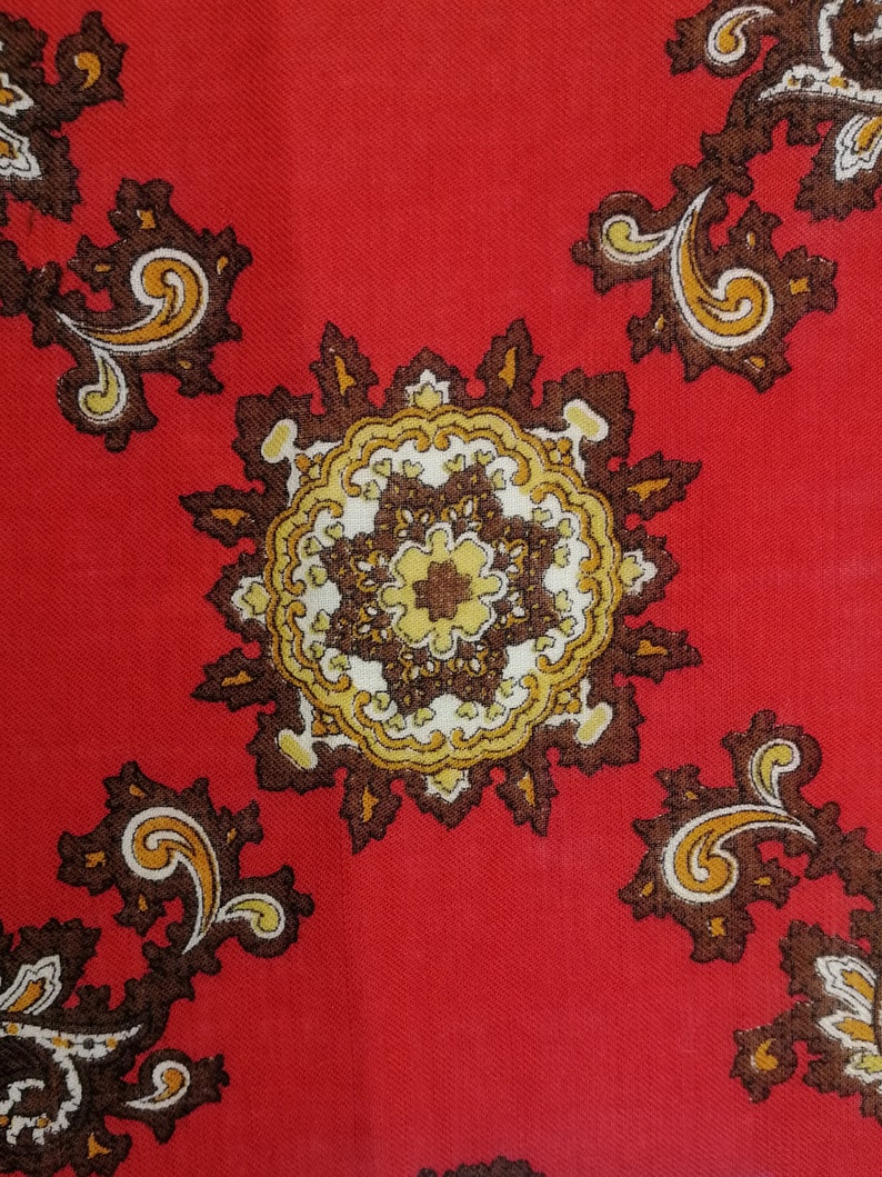 K&ouml;nnte beinhalten: Roter Stoff mit einem Paisley-Muster in Braun, Gold und Wei&szlig;. Das Muster zeigt komplizierte Wirbel und florale Motive.